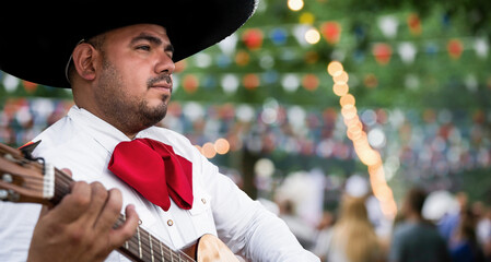 Mexican musician mariachi with guitar on a blurred party background	
