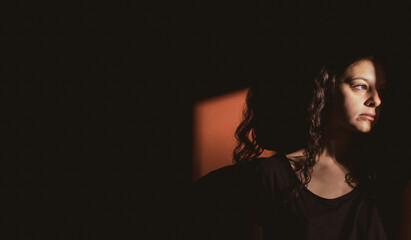 young woman on black background with light and shadow on face