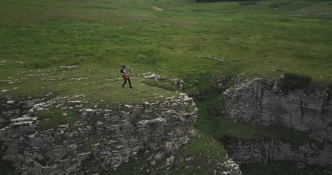 Dolly aerial shot, a man plays rock guitar on his own in a natural par