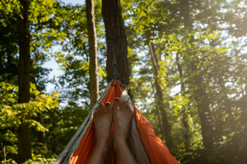 POV shot of woman's painted toe nails in hammock in a green forest - Powered by Adobe