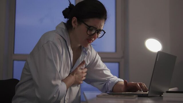Young woman feeling sudden pain in chest working on laptop, risk of heartattack
