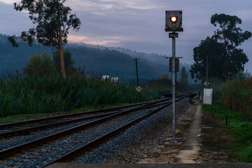 Landscape with railway semaphore and tracks against hills in fog