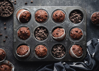 Overhead of tin of chocolate zucchini muffins on black background.