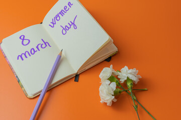 Notepad for International Women's Day, with white flowers and purple pencil