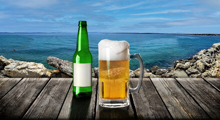 Beer mug and bottle on a wood table on a mediterranean beach