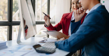Fototapeta premium Business documents on office table with smart phone and laptop and two colleagues discussing data in the background in morning light