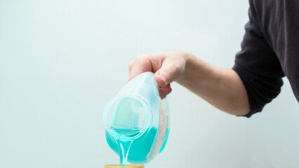 Pouring laundry detergent from bottle into cap. Close up of male hands pouring liquid laundry detergent into cap.