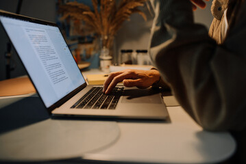 A man edits a text, writes an article, studies at a laptop in the kitchen in the evening