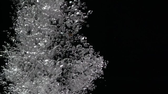 Macro shot of air bubbles rising in slow motion in water on a black background isolated. Boiling water. slow mo 200 fps