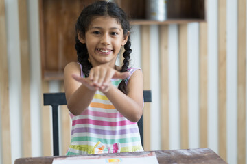 Happy child girl playing with her hands in the living room at home