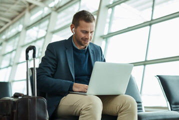 Airport, business man and laptop for music during travel or working in lobby streaming internet....