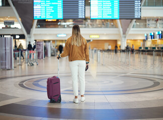 Woman, airport and luggage checking flight times for travel, vacation or journey with passport in...