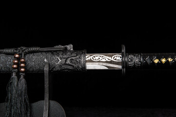 Long Chinese sword with black scabbard on black background.