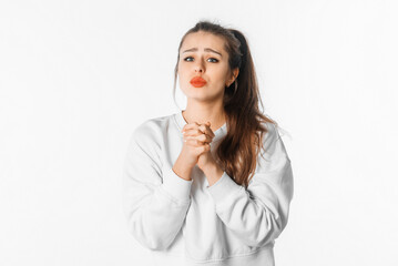 Hopeful young woman clenching fists making wish praying asking dreams come true. Brunette girl...