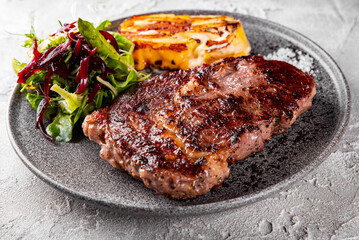 Grilled Ribeye Steak on plate with cheese and salad