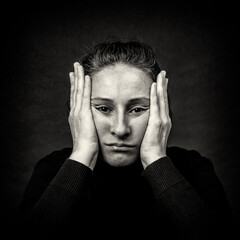 Conceptual dark portrait of unhappy woman with hands over her head stretching face in ugly grimace....