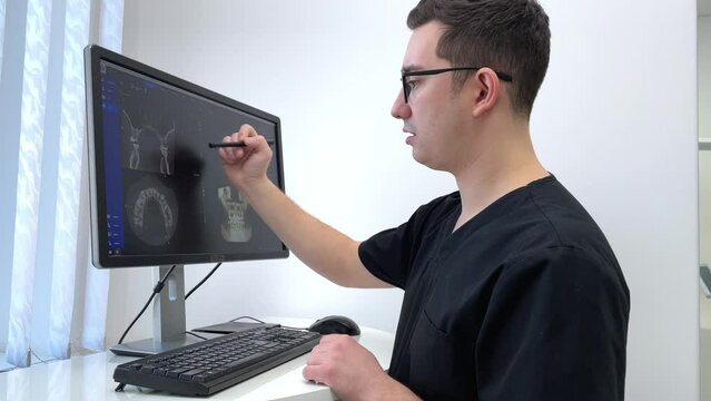 Dentist doctor examines a panoramic x-ray of the jaw on a computer screen. The doctor shows a 3D model of the patient's mouth, MRI scan. Diagnostic equipment for teeth in a modern dental clinic.