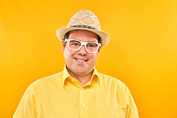 Portrait of positive fat man in hat kindly smiling isolated on yellow studio background, travel vacation concept