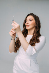 young woman doctor in a white coat holds an insulin syringe in her hand. Girl cosmetologist...