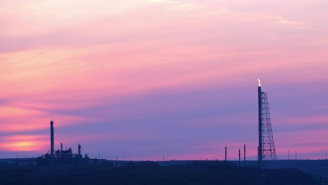 Fire from a pipeline. Oil production. Working oil refinery. Smoke from the factory chimney. Air emissions polluting the city. Gas pipeline at sunset. petroleum-producing