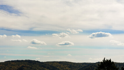 Landscape of clouds, blue sky and forested mountains