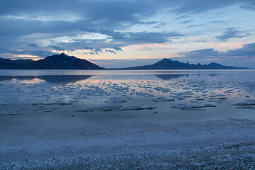 Scenic view of beautiful mountains reflecting in lake of Bonneville Salt Flats at sunset, Wendover, Western Utah, USA, America. Looking at summits of Silver Island Mountain range. Romantic atmosphere