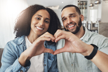Love, heart hand sign and portrait couple enjoy quality time together, bonding or relax on home living room sofa. Happiness, emoji gesture or happy marriage people, man or woman in good health