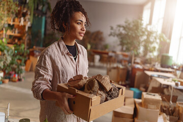 Fototapeta premium Woman holds box with handmade wooden props in a home decor studio. Blurred background