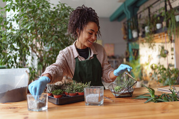 Happy smiling woman florist making succulent plant composition at floral design studio