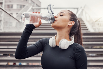 Workout, hydration and a sports woman drinking water outdoor in the city during cardio or endurance exercise. Runner, fitness and hydrated with a female athlete training in an urban town for health - Powered by Adobe