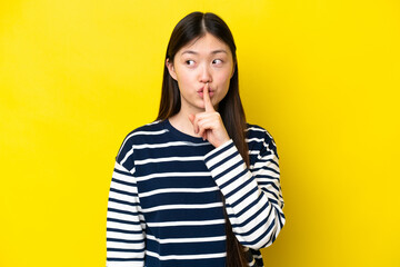 Young Chinese woman isolated on yellow background showing a sign of silence gesture putting finger in mouth