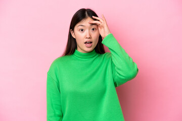 Young Chinese woman isolated on pink background doing surprise gesture while looking front