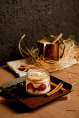 a jar of Magnolia, one of the milky and fruity desserts, poses with a milk pot and cinnamon in the back.