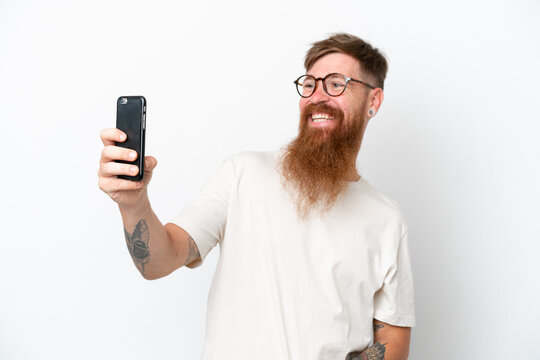 Redhead man with long beard isolated on white background making a selfie