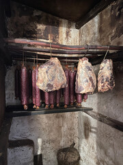 Schinken und Salami hängen in einem Räucherofen