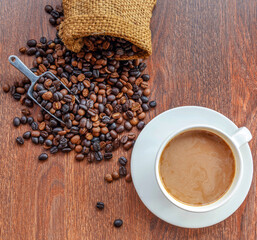 cup of coffee and coffee beans in a sack on  Brown background, top view