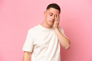 Young Brazilian man isolated on pink background with headache