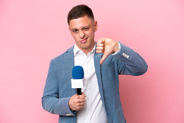 Young brazilian presenter man isolated on pink background showing thumb down with negative expression