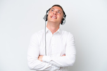 Telemarketer Brazilian man working with a headset isolated on white background looking up while smiling