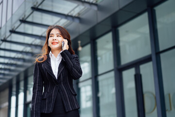 Fototapeta premium Business woman talking on mobile phone and smiling, Happy business woman, business woman with mobile phone in hand looking at camera, Image of pretty smiling woman in fashion