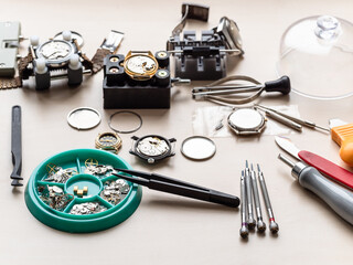 spare parts, tools and old watches on wooden table in watchmaker workshop