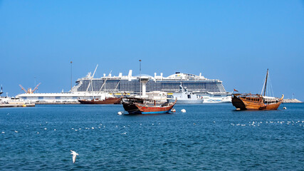 Old sailing boat anchored at the Muttrah Corniche. Muscat old town and mountains in the background, Oman