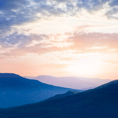 Fototapeta na wymiar mountain ridge silhouette in dense mist at the sunset, natural mountain travel background