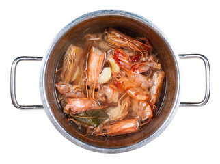 top view of saucepan with boiled heads and shells of shrimp cutout on white background