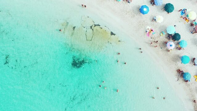 Aerial drone top down view of the beautiful beach and turquoise sea of marina di Pulsano, Taranto, Italy, Salento, in the summer with colorful umbrellas