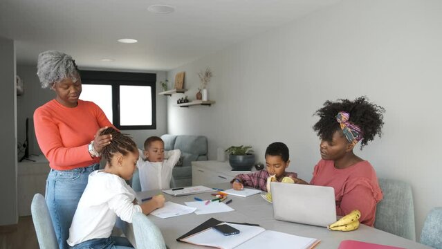African family having a snack while painting or doing the homework. Horizontal extended family spending time together.