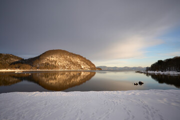 雪の中、夕焼けに照らされる猪苗代湖