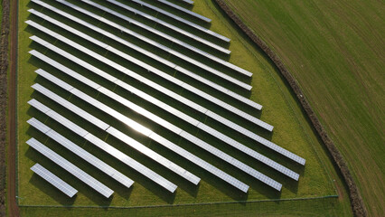 Solar panel farm aerial view with good copy space. Fields full of solar panels sit in green grassy fields producing clean zero carbon energy. Solar energy production