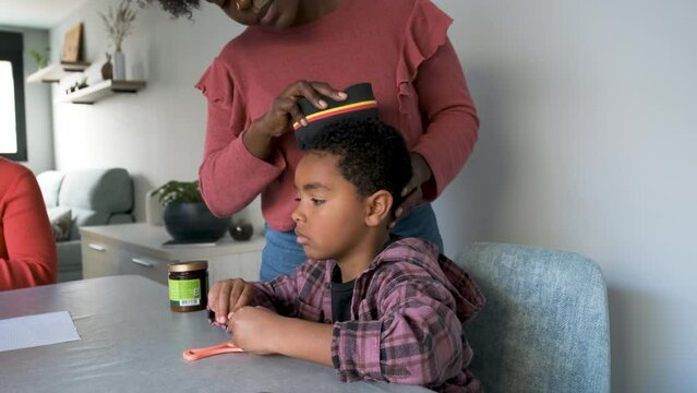 African mother styling her son hair using an afro curl wave or twists sponge.