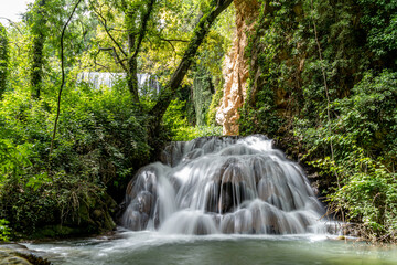 Fototapeta premium Cascade of multiple waterfalls in the middle of nature surrounded by trees and green vegetation.